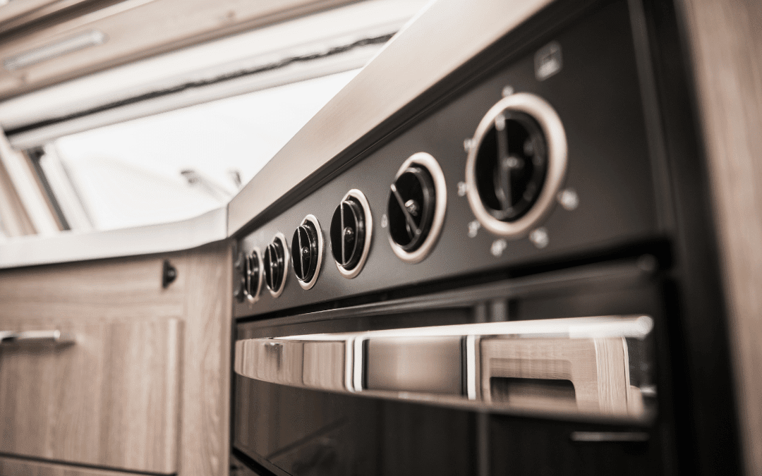 Modern RV kitchen oven and control panel with stainless steel finishes after custom renovation