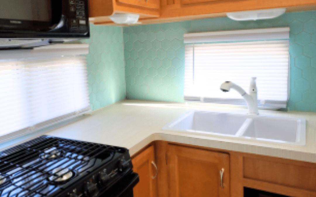 Modern renovated RV kitchen with double sink, black stovetop, wood cabinets, and bright backsplash after custom renovation
