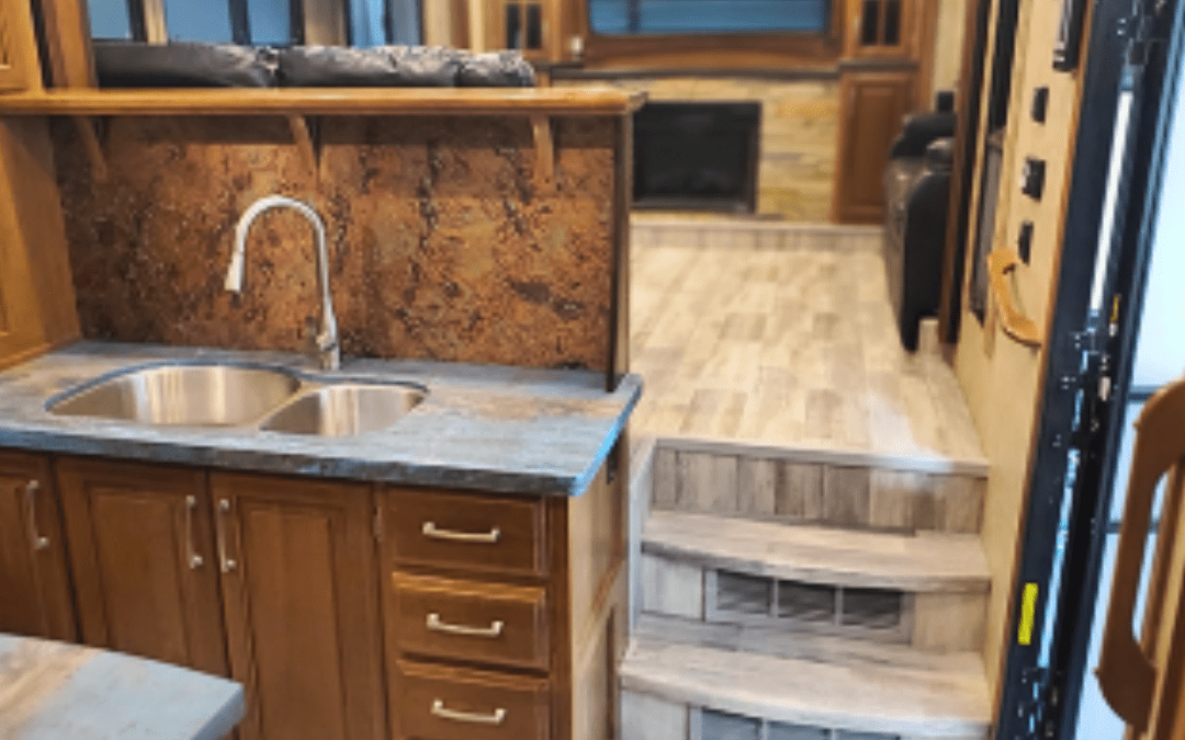 Renovated RV kitchen with double stainless steel sink, wood cabinets, and custom countertops at Ace of Spades Custom RV and Repair