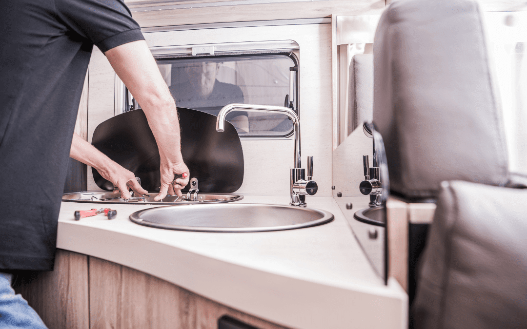 Technician installing new stainless steel sink and faucet during custom RV kitchen renovation at Ace of Spades Custom RV and Repair