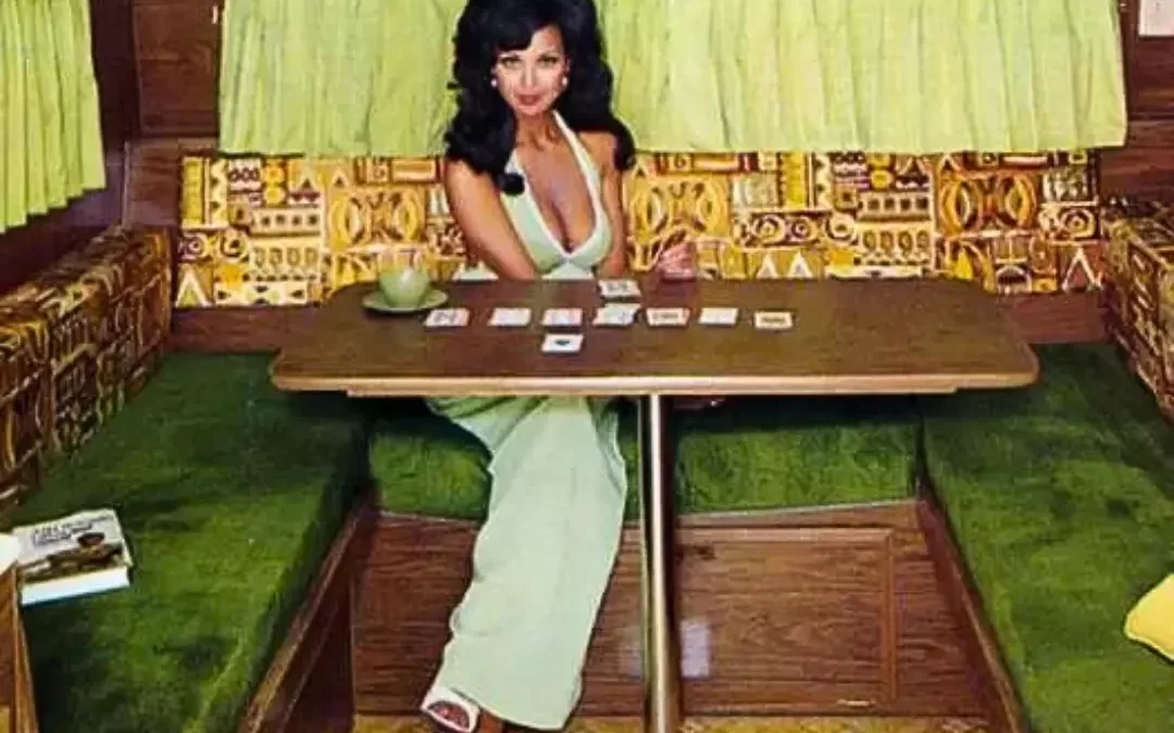 Woman in 1970s retro fashion sitting inside a classic vintage camper with green shag carpet and wood paneling, embracing vintage trailer culture