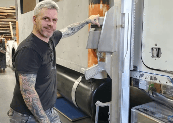 Builder of the Barrett Truck standing beside a custom aluminum component during the fabrication of the 1998 Peterbilt conversion