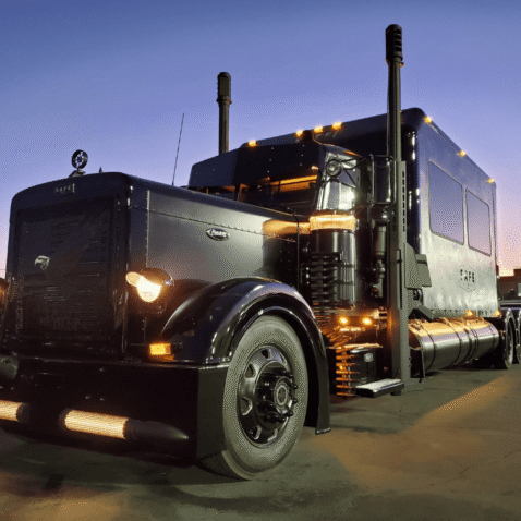Black Barrett Truck custom 1998 Peterbilt conversion featuring handcrafted Barrett 50 Caliber smoke stacks and LED lighting at dusk