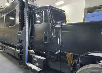 Side view of the Barrett Truck custom 1998 Peterbilt conversion in the workshop showing the cab, steps, and custom bodywork