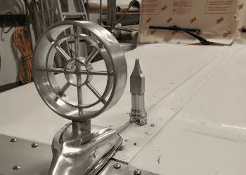 Custom polished aluminum hood ornament on the Barrett Truck, a fully custom Peterbilt build featuring intricate spoked wheel design and streamlined base