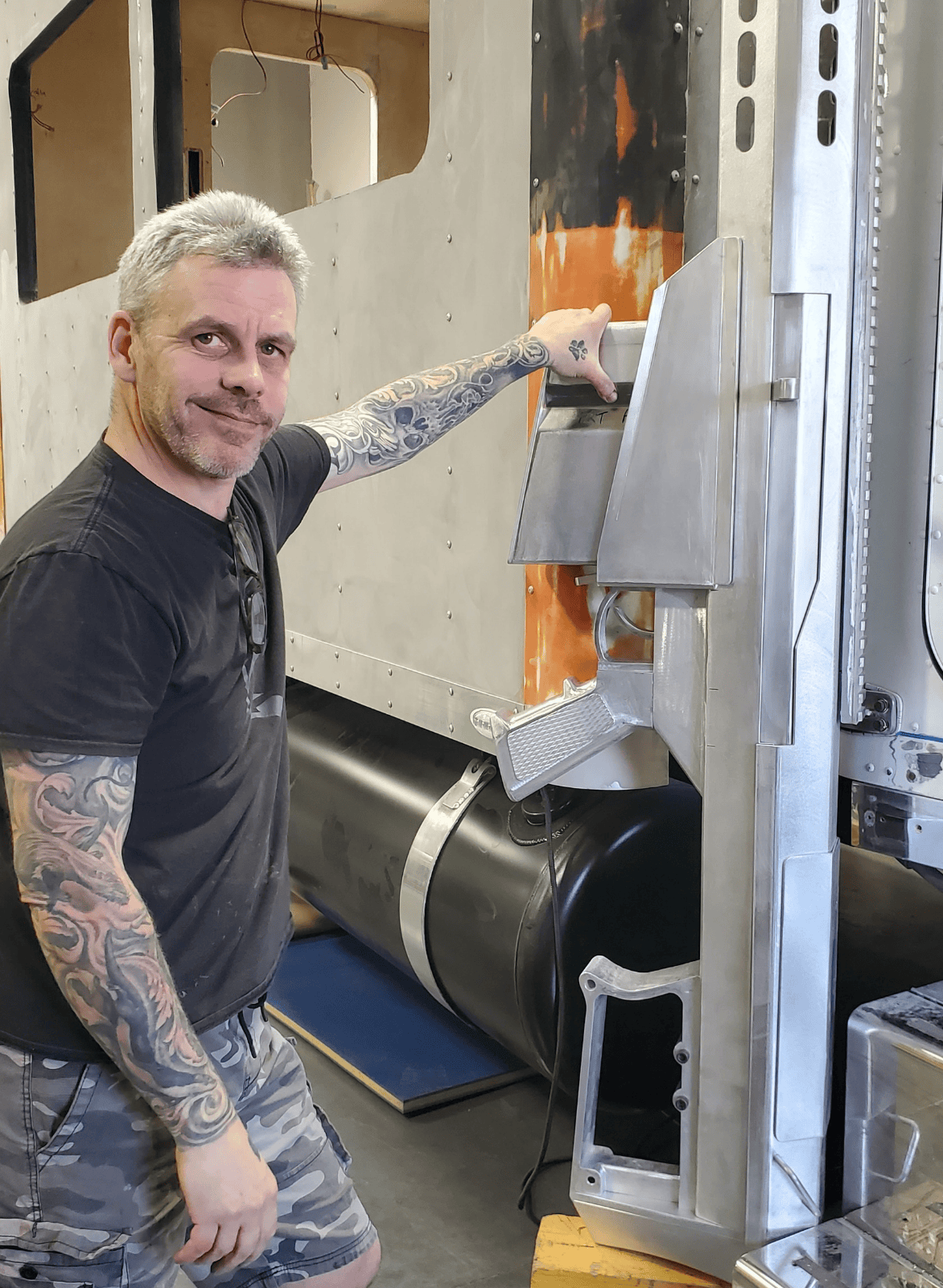 James West owner of Ace of Spades Custom RV standing with custom aluminum welded smoke stack on Peterbilt truck